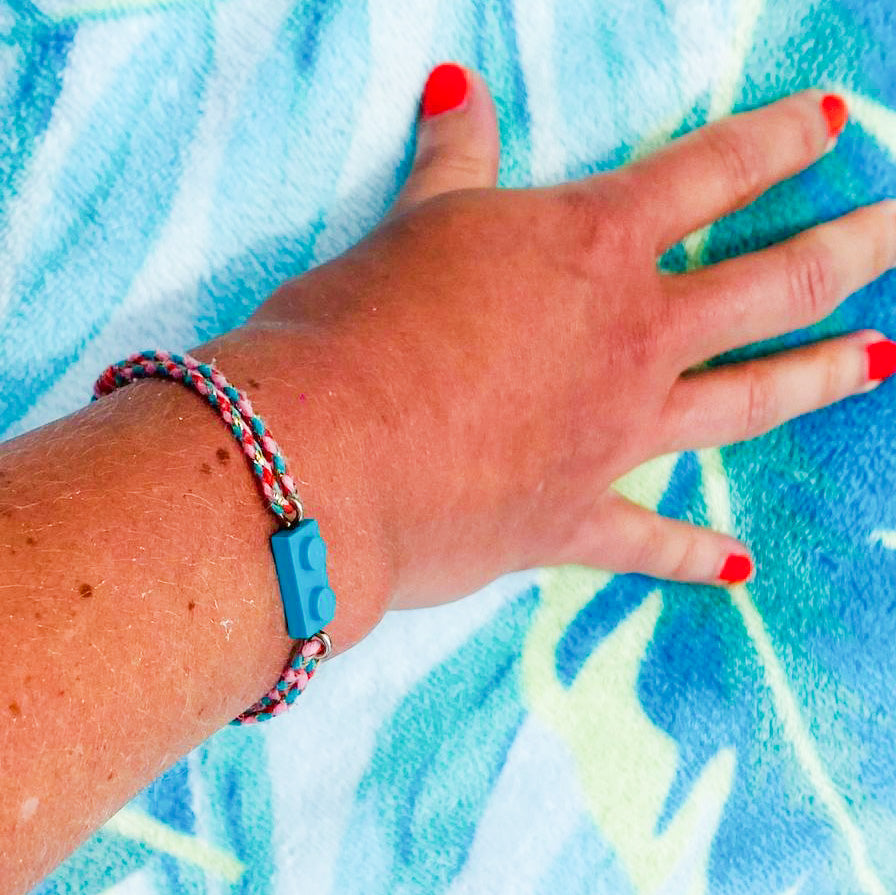 Adjustable braided coral-green cord bracelet with matching Lego brick