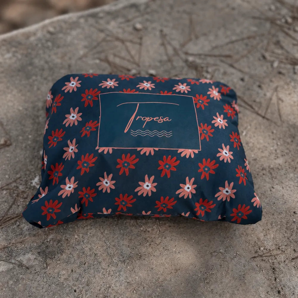 Poncho de pluie Paola bleu marine à fleurs marguerites plié dans sa pochette