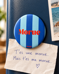 Magnet Muisti « Morue » tenant un petit mot dans une scène du quotidien.