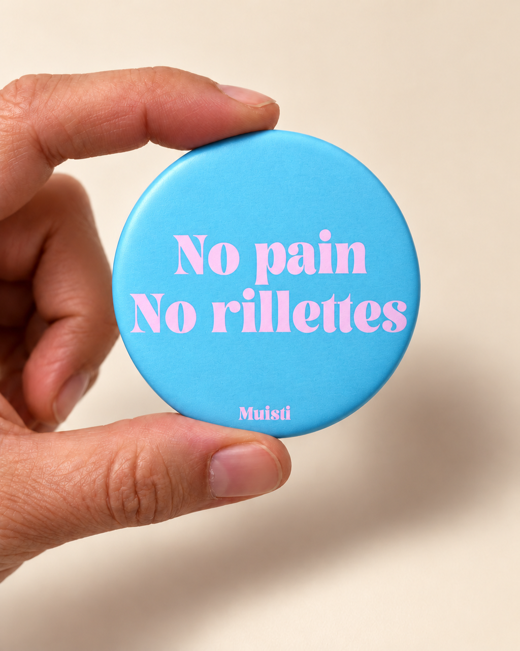 Magnet Muisti « No pain No rillettes » tenu entre le pouce et l’index sur fond ivoire.