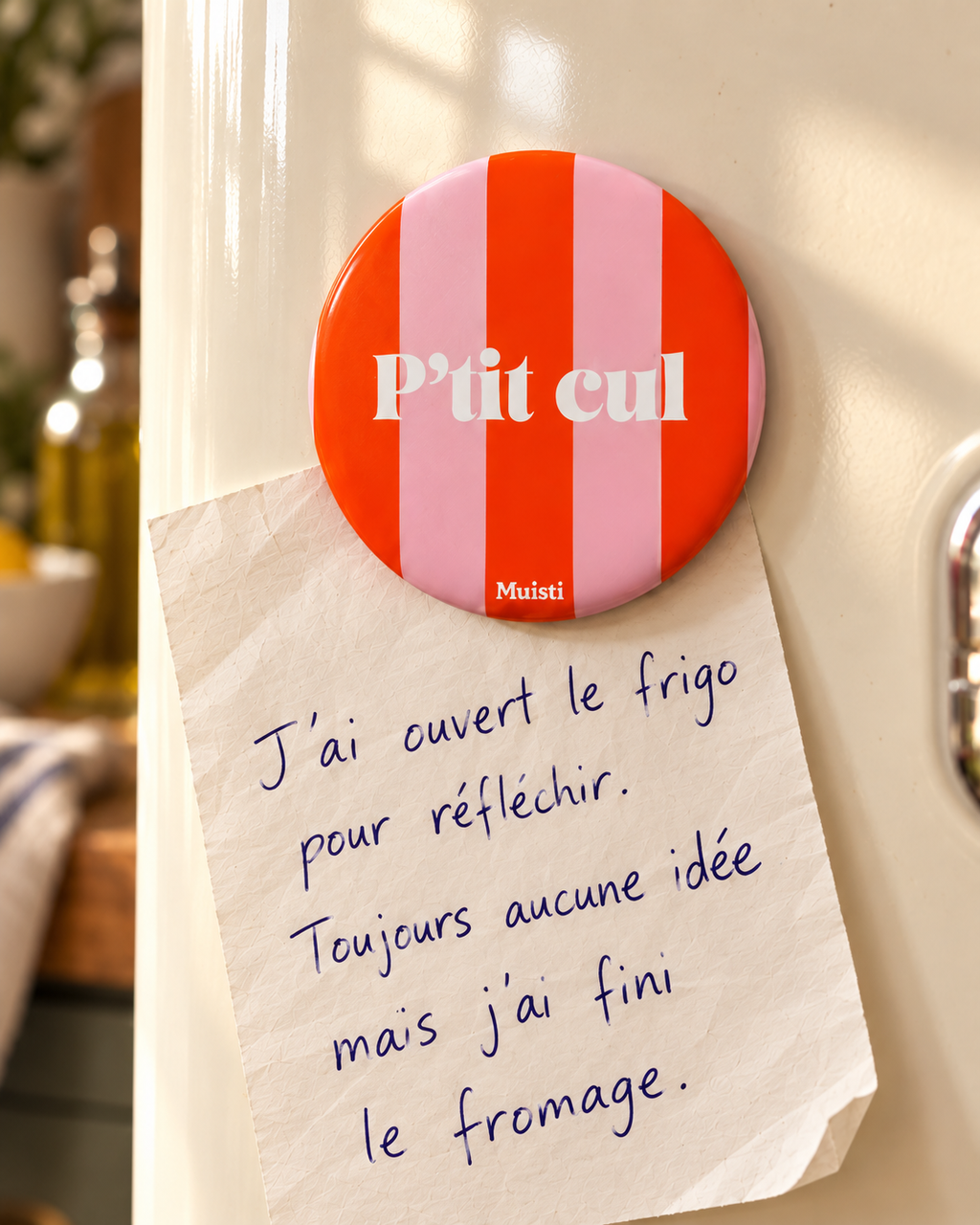 Magnet Muisti « P’tit cul » en gros plan sur un réfrigérateur ivoire, tenant un mot manuscrit.