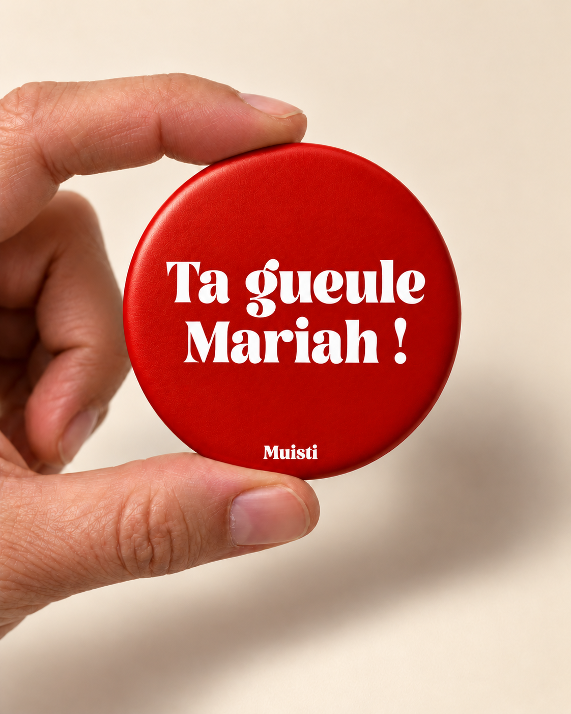 Magnet Muisti « Ta gueule Mariah ! » tenu entre le pouce et l’index sur fond ivoire.