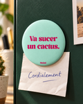 Magnet Muisti « Va sucer un cactus. » tenant un petit mot dans une scène du quotidien.