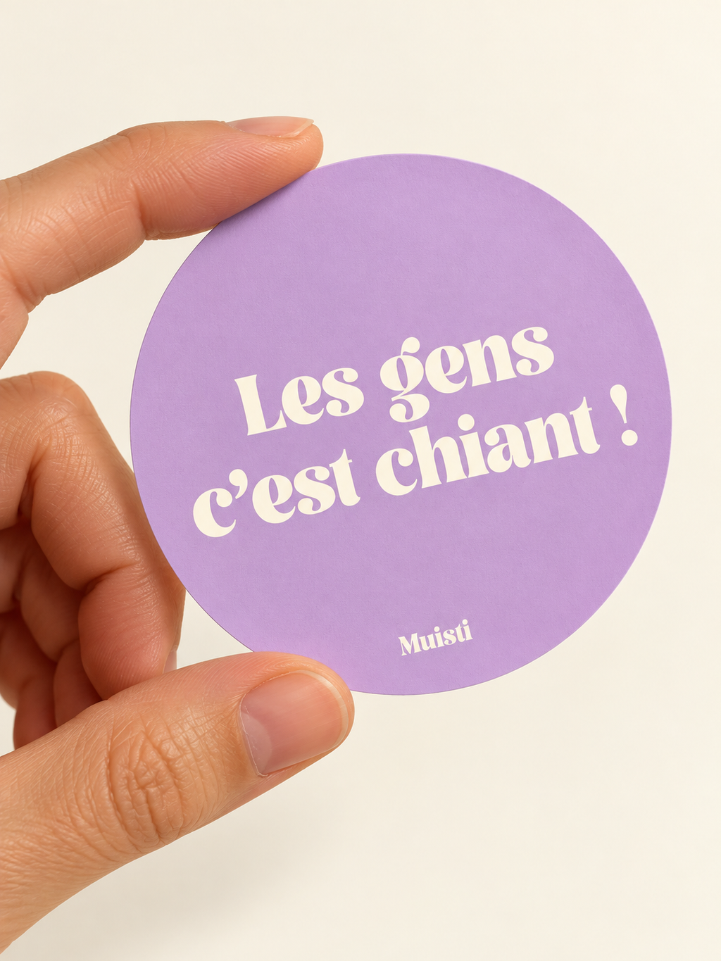 Sticker Muisti Les gens c’est chiant ! tenu entre le pouce et l’index sur fond ivoire